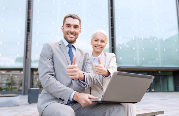 Glimlachende zakenmensen met laptop outdoors — Stockfoto