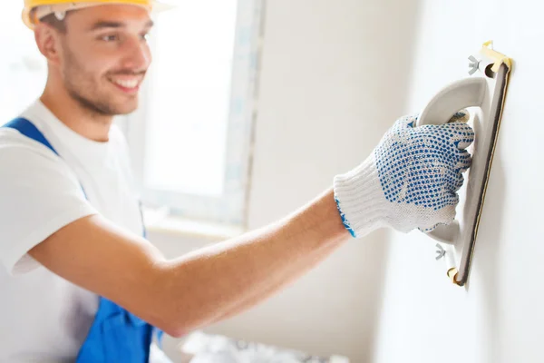 Construtor sorrindo com ferramenta de moagem dentro de casa — Fotografia de Stock