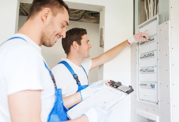 Builders with clipboard and electrical panel — Stock Photo, Image
