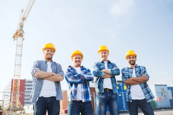 Groep van lachende bouwers in hardhats in openlucht — Stockfoto