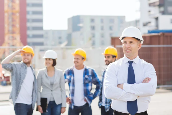 Gruppo di costruttori sorridenti in hardhats all'aperto — Foto Stock