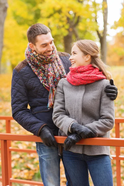 Χαμογελαστά, ζευγάρι αγκαλιάζει στη γέφυρα στο πάρκο φθινόπωρο — Φωτογραφία Αρχείου