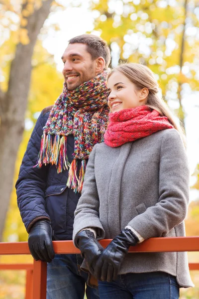 Smiling couple hugging on bridge in autumn park — Stock Photo, Image