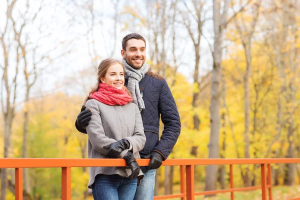 Smiling couple hugging on bridge in autumn park — Stock Photo, Image
