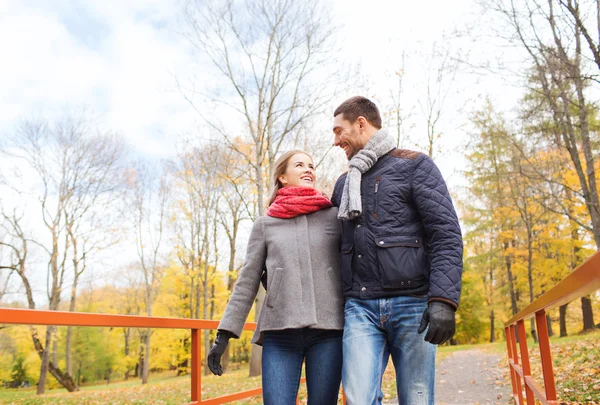 Casal sorridente abraçando na ponte no parque de outono — Fotografia de Stock