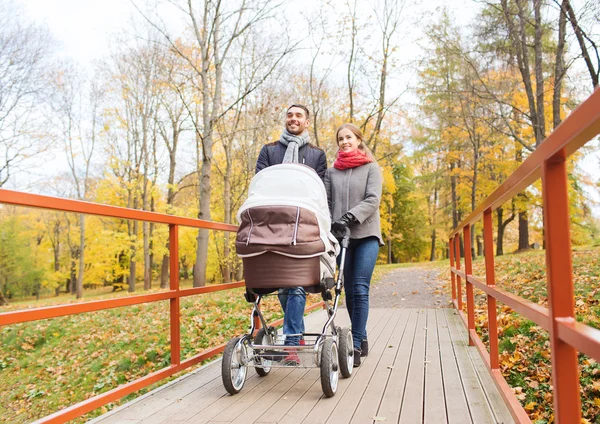 Lachende paar met baby pram in herfst park — Stockfoto