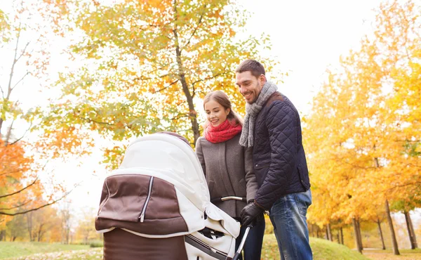 Lachende paar met baby pram in herfst park — Stockfoto