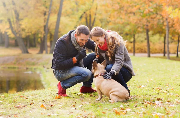 Sonriente pareja con perro en otoño parque — Foto de Stock