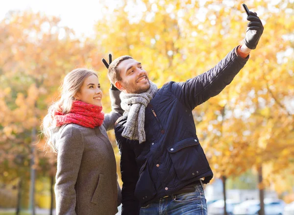 Lachende paar met smartphone in herfst park — Stockfoto