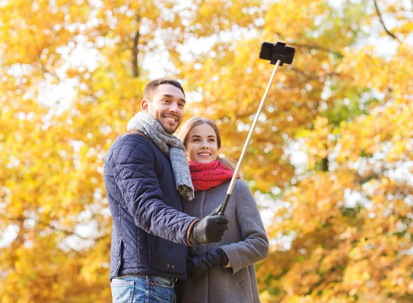 Усміхнена пара зі смартфоном в осінньому парку — стокове фото