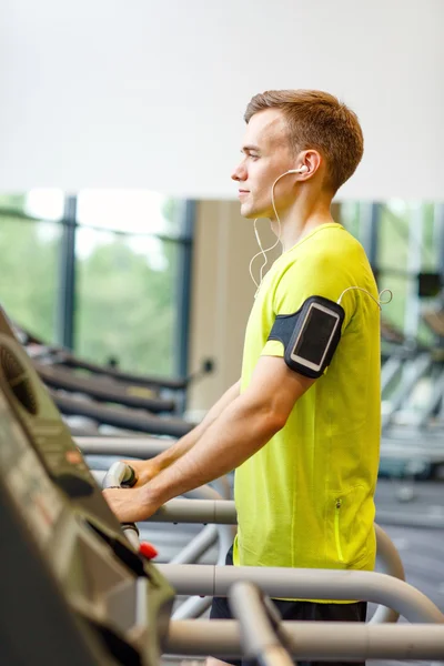 Человек со смартфоном тренируется на беговой дорожке в тренажерном зале — стоковое фото