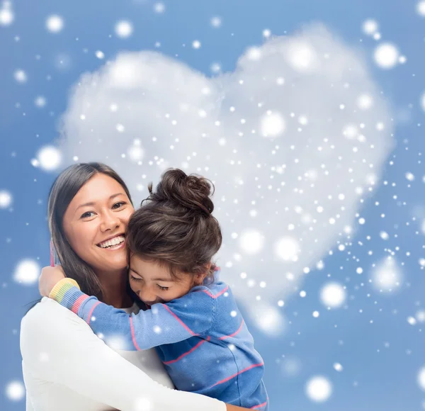 Smiling little girl and mother hugging indoors — Stock Photo, Image