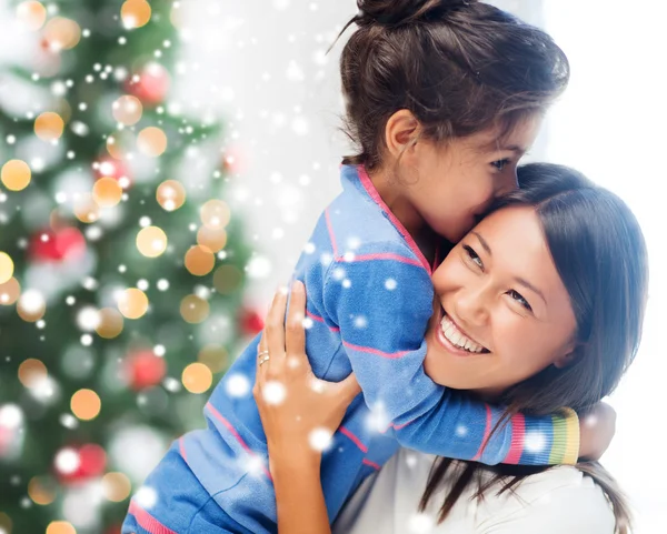 Smiling little girl and mother hugging indoors — Stock Photo, Image