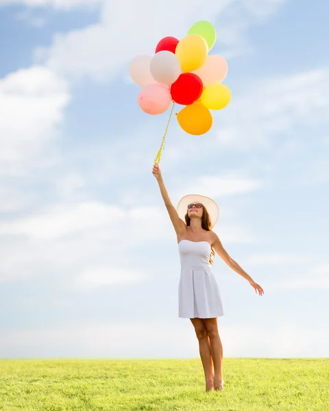 Gülümseyen güneş gözlüğü balonlarla genç kadın — Stok fotoğraf