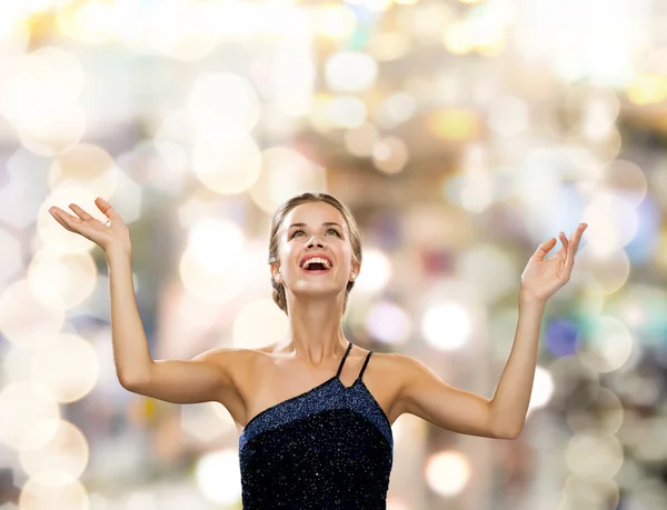 Smiling woman raising hands and looking up — Stock Photo, Image