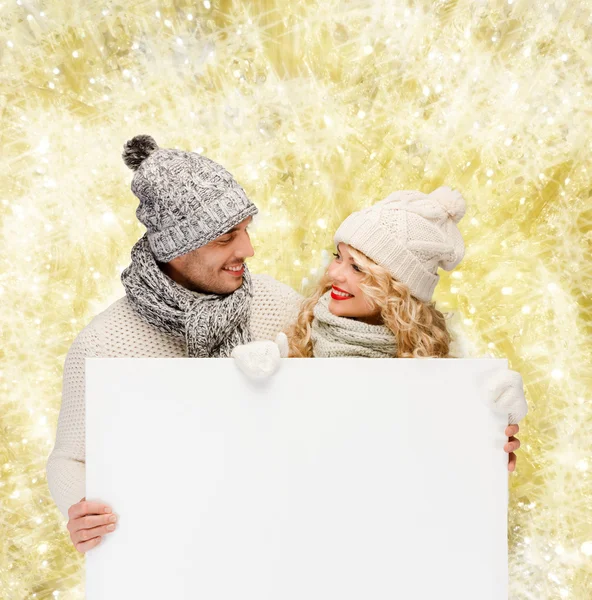 Lachende paar in winterkleren met wit bord — Stockfoto