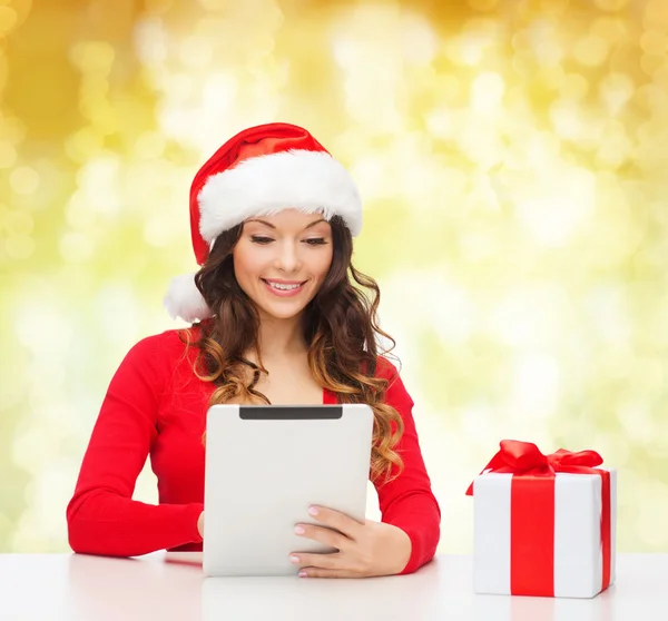 Donna sorridente in cappello di Babbo Natale con regalo e tablet pc — Foto Stock