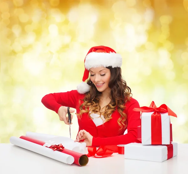 Smiling woman in santa helper hat packing gift box — Stock Photo, Image