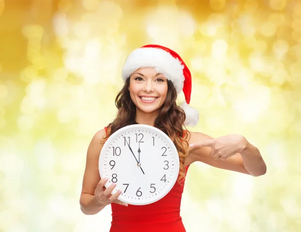 Femme souriante dans santa chapeau d'aide avec horloge — Photo