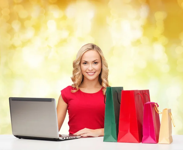 Mulher sorridente em camisa vermelha com presentes e laptop — Fotografia de Stock