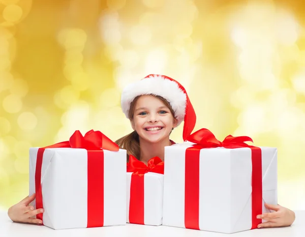 Sonriente chica en santa helper sombrero con cajas de regalo —  Fotos de Stock