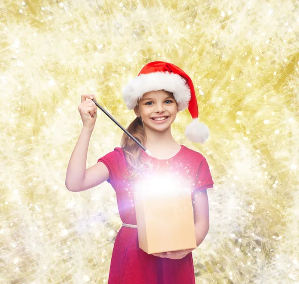 Chica sonriente en sombrero de ayudante de santa con caja de regalo — Foto de Stock