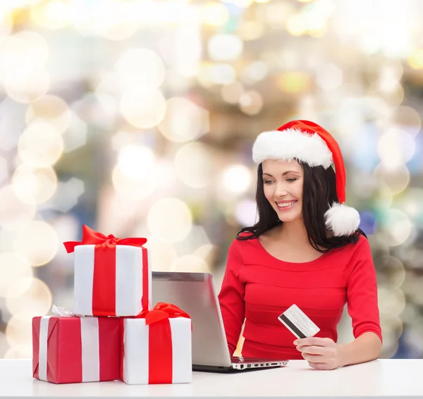Lachende vrouw met geschenken, laptop en credit card — Stockfoto