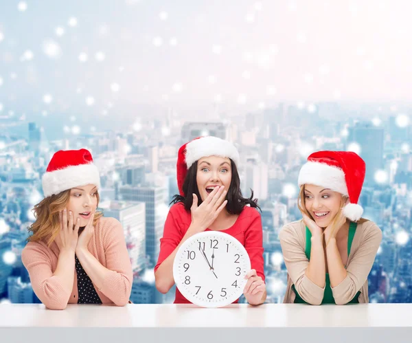 Donne sorridenti in cappelli Babbo Natale aiutante con orologio — Foto Stock