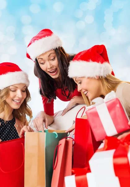 Sonrientes mujeres jóvenes en sombreros de santa con regalos —  Fotos de Stock