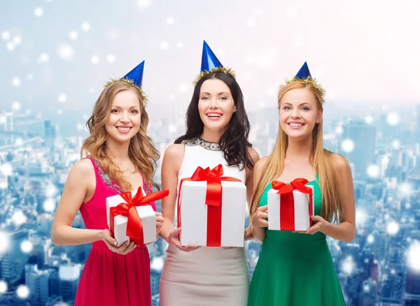 Lächelnde Frauen in Partymützen mit Geschenkboxen — Stockfoto