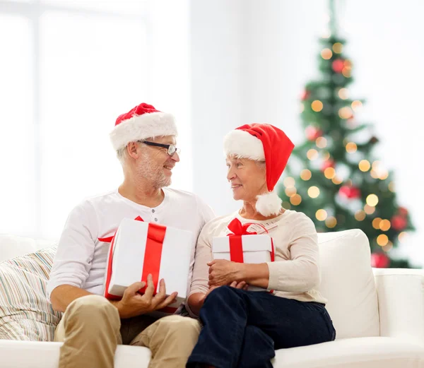 Feliz pareja de ancianos en sombreros de santa con cajas de regalo —  Fotos de Stock
