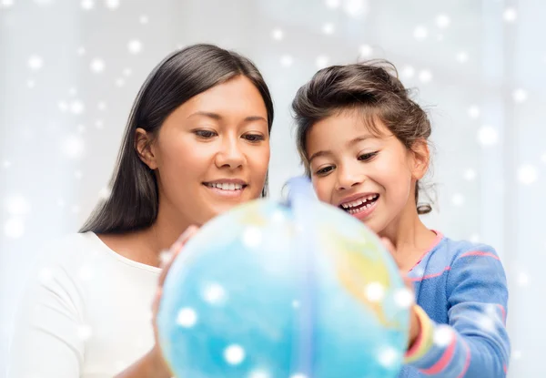 Mother and daughter with globe indoors — Stock Photo, Image