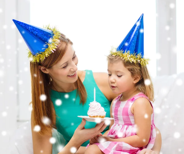 Mutter und Tochter in Partyhüten mit Kuchen — Stockfoto