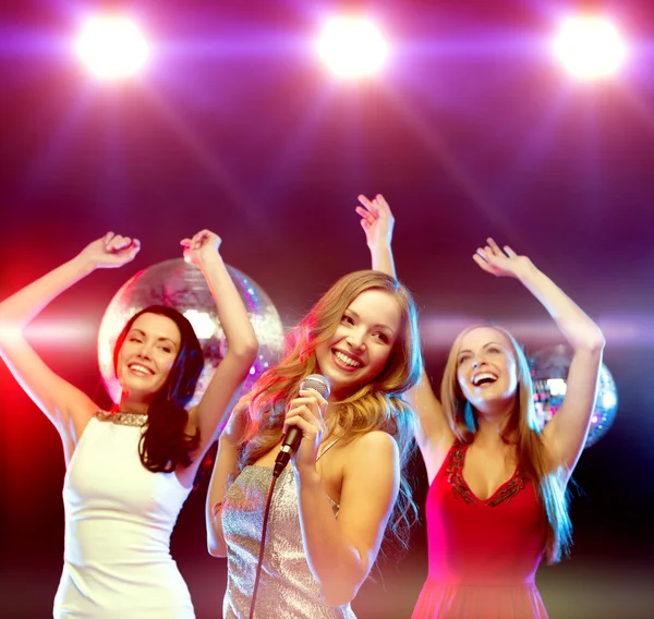 Tres mujeres sonrientes bailando y cantando karaoke — Foto de Stock