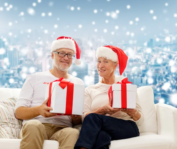 Gelukkig senior koppel in santa hoeden met geschenkdozen — Stockfoto
