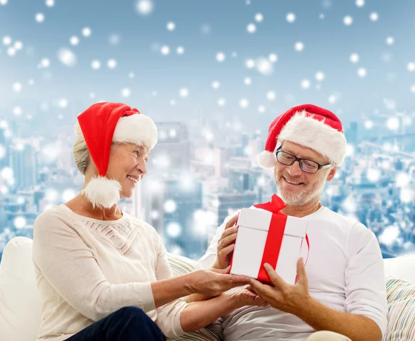 Gelukkig senior koppel in santa hoeden met doos van de gift — Stockfoto