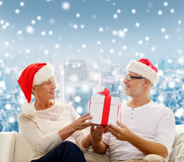 Feliz pareja de ancianos en sombreros de santa con caja de regalo — Foto de Stock