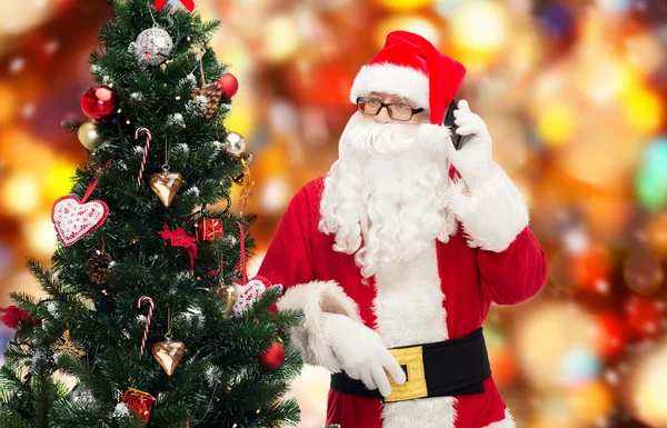 Santa claus com smartphone e árvore de natal — Fotografia de Stock