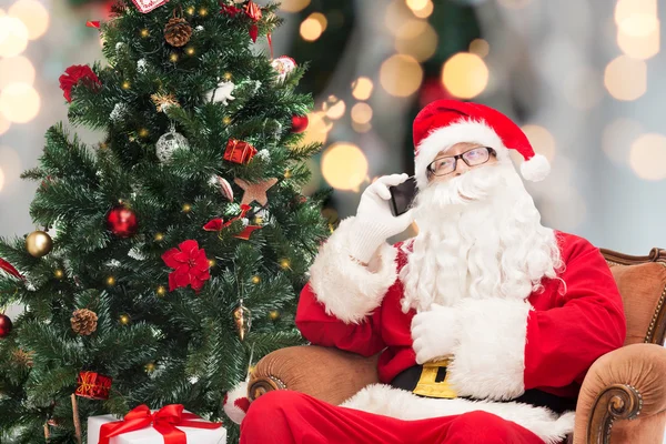 Santa claus with smartphone and christmas tree — Stock Photo, Image