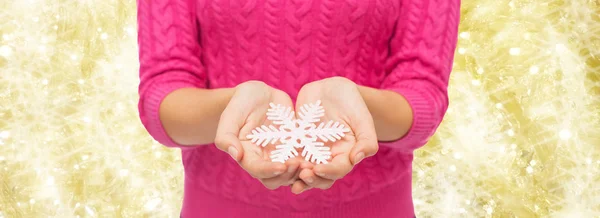 Close up of woman in sweater holding snowflake — Stock Photo, Image