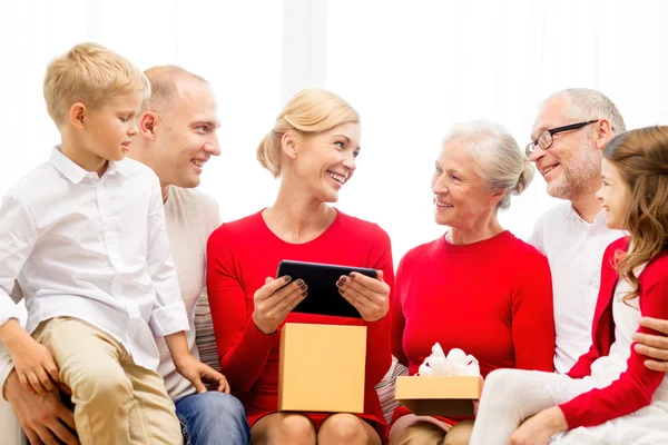 Família sorrindo com tablet pc e caixa de presente em casa — Fotografia de Stock