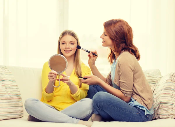 Two smiling teenage girls applying make up at home — Stock Photo, Image