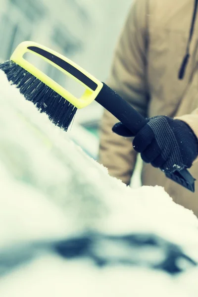 Homem limpando a neve do pára-brisas do carro com escova — Fotografia de Stock