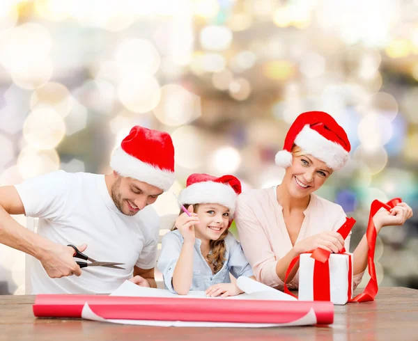 Famiglia felice in cappelli Babbo Natale helper imballaggio regalo — Foto Stock