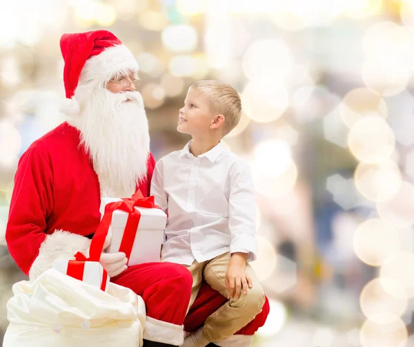 Niño sonriente con santa claus y regalos — Foto de Stock