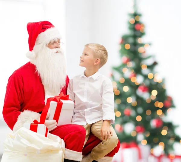 Petit garçon souriant avec santa claus et cadeaux — Photo