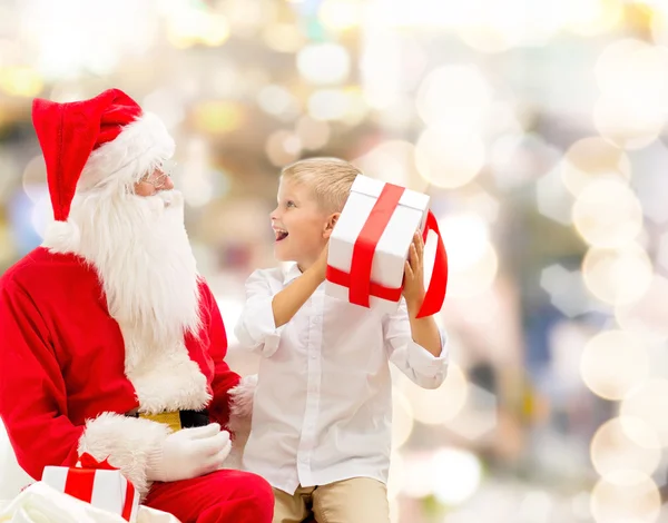 Petit garçon souriant avec santa claus et cadeaux — Photo