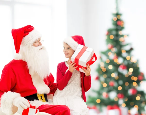 Lächelndes kleines Mädchen mit Weihnachtsmann und Geschenken — Stockfoto