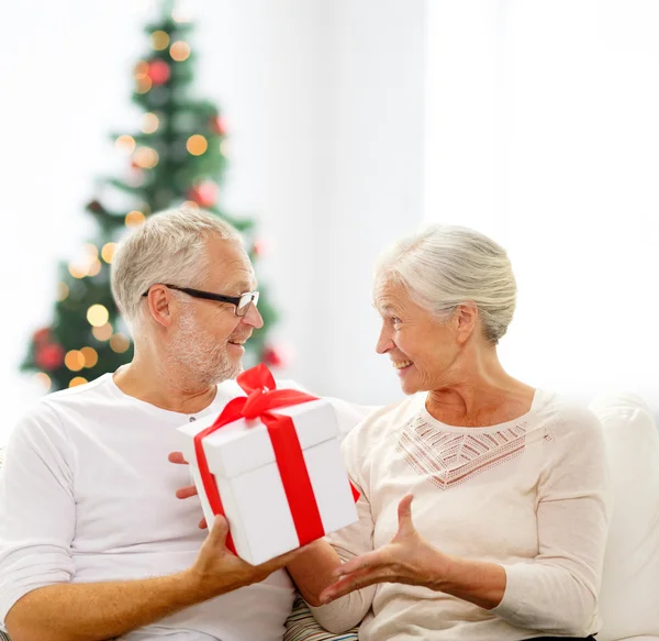 Feliz pareja de ancianos con caja de regalo en casa — Foto de Stock