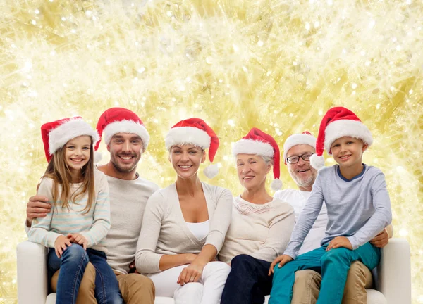 Feliz familia en santa helper sombreros sentado en el sofá —  Fotos de Stock